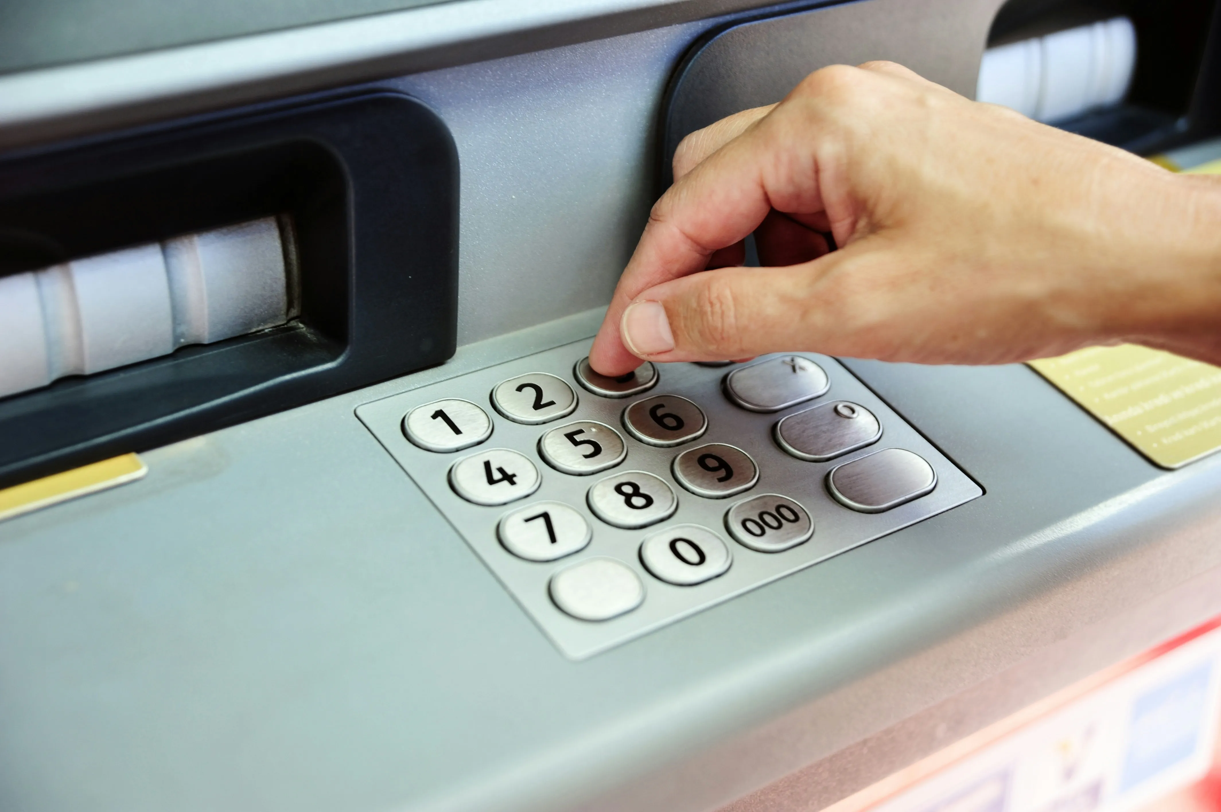 A hand entering a PIN on an ATM keypad