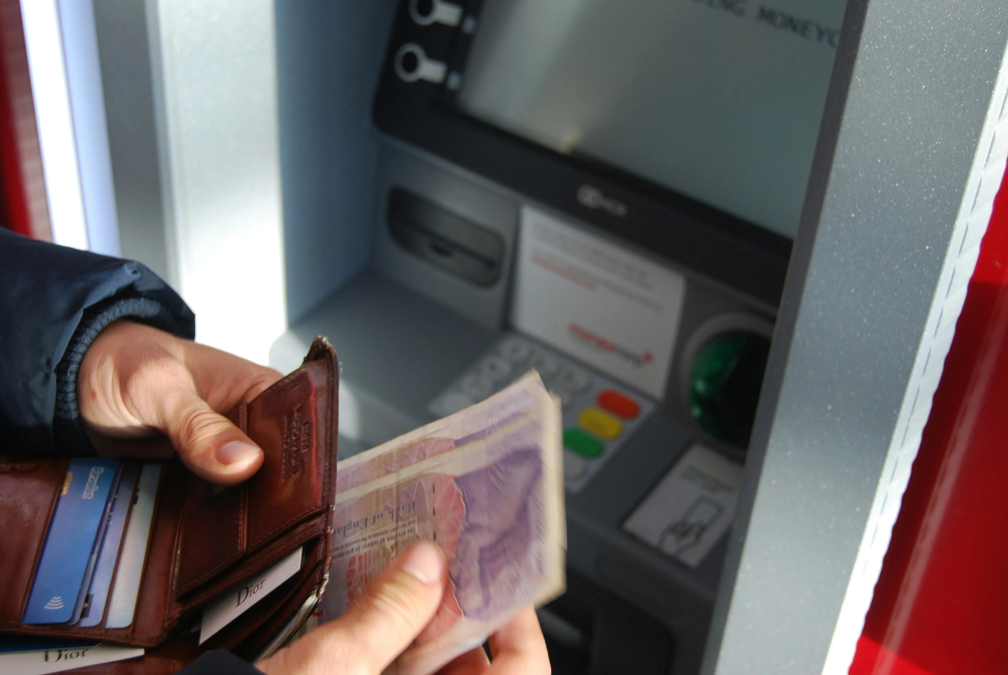 A person taking banknotes from an ATM cash slot