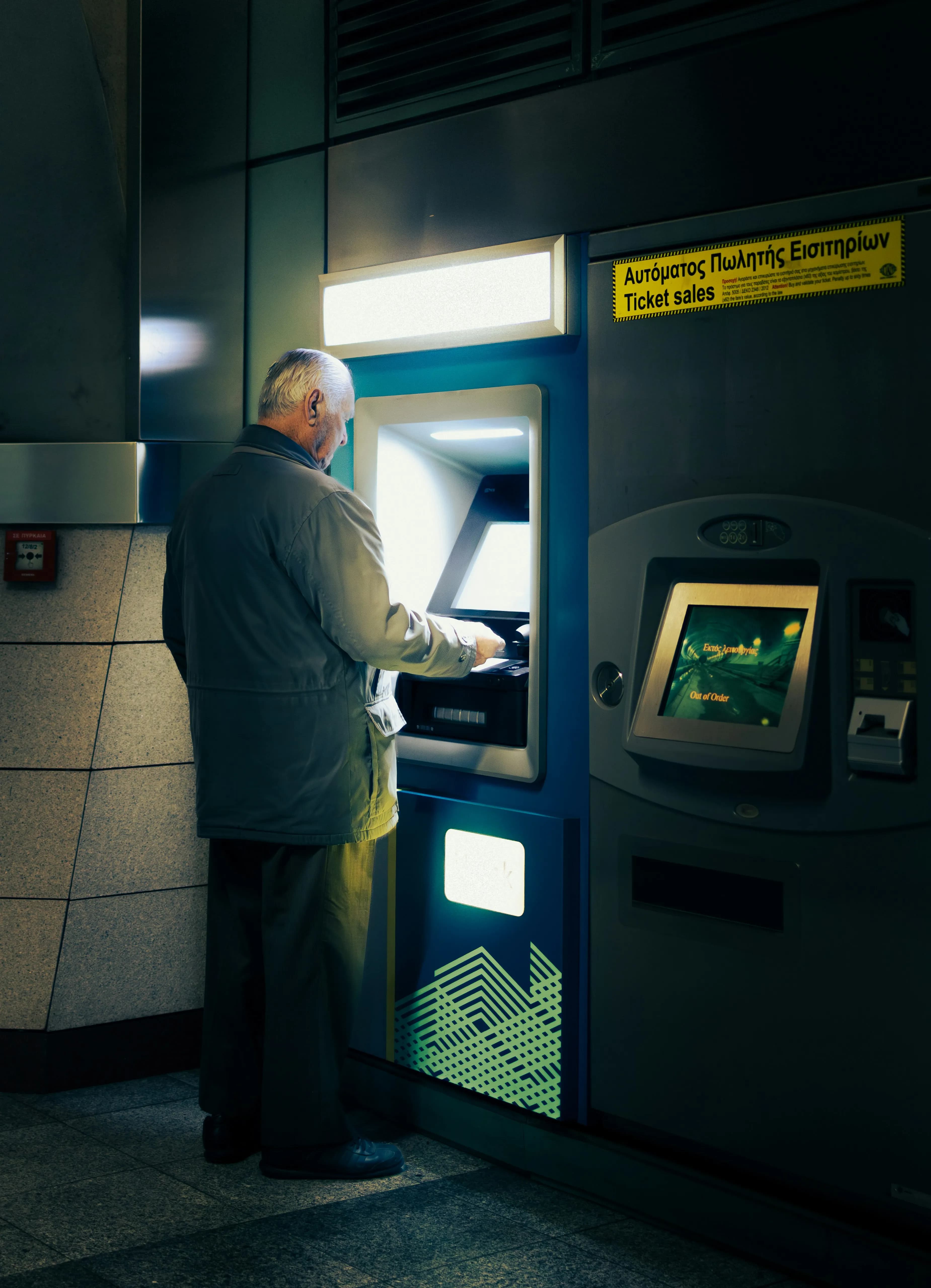 An older man using a cash machine at night