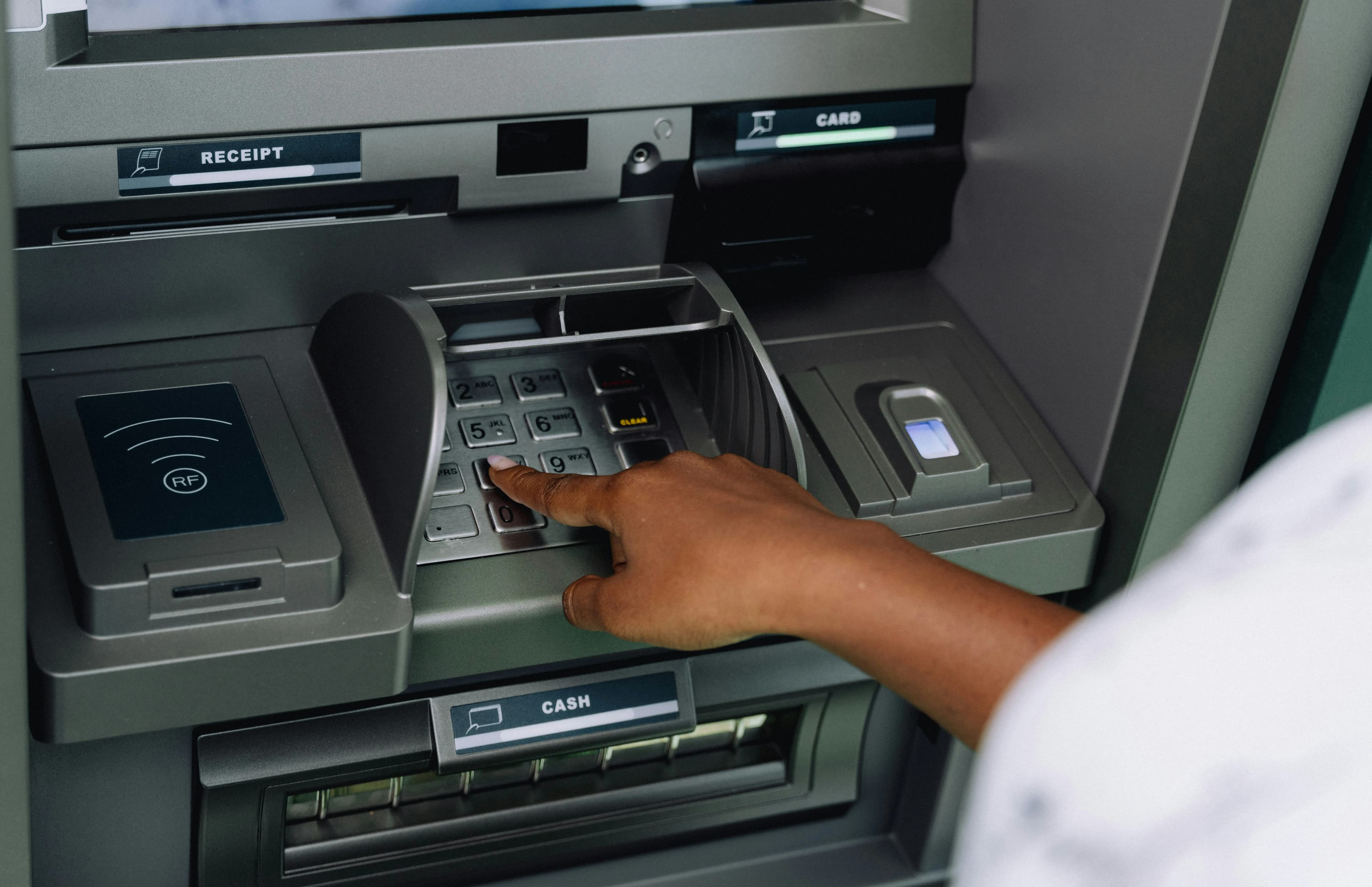 A person entering a PIN on an ATM keypad